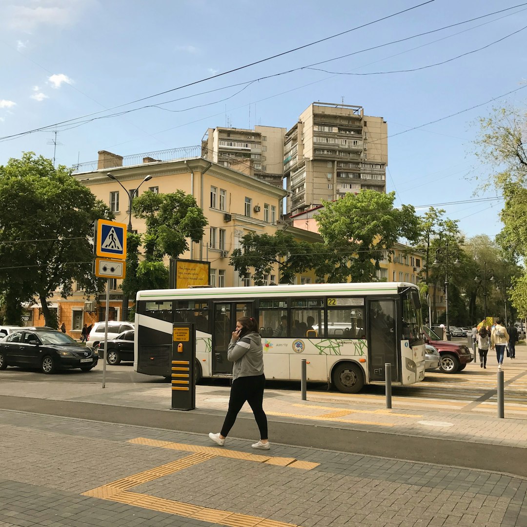 woman using phone at sidewalk with vehicles on road
