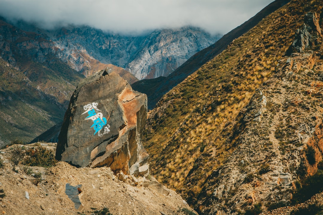 Muktinath track View valley Himalayan mountain Nepal by Chile Vacay a rock with a picture of a person painted on it