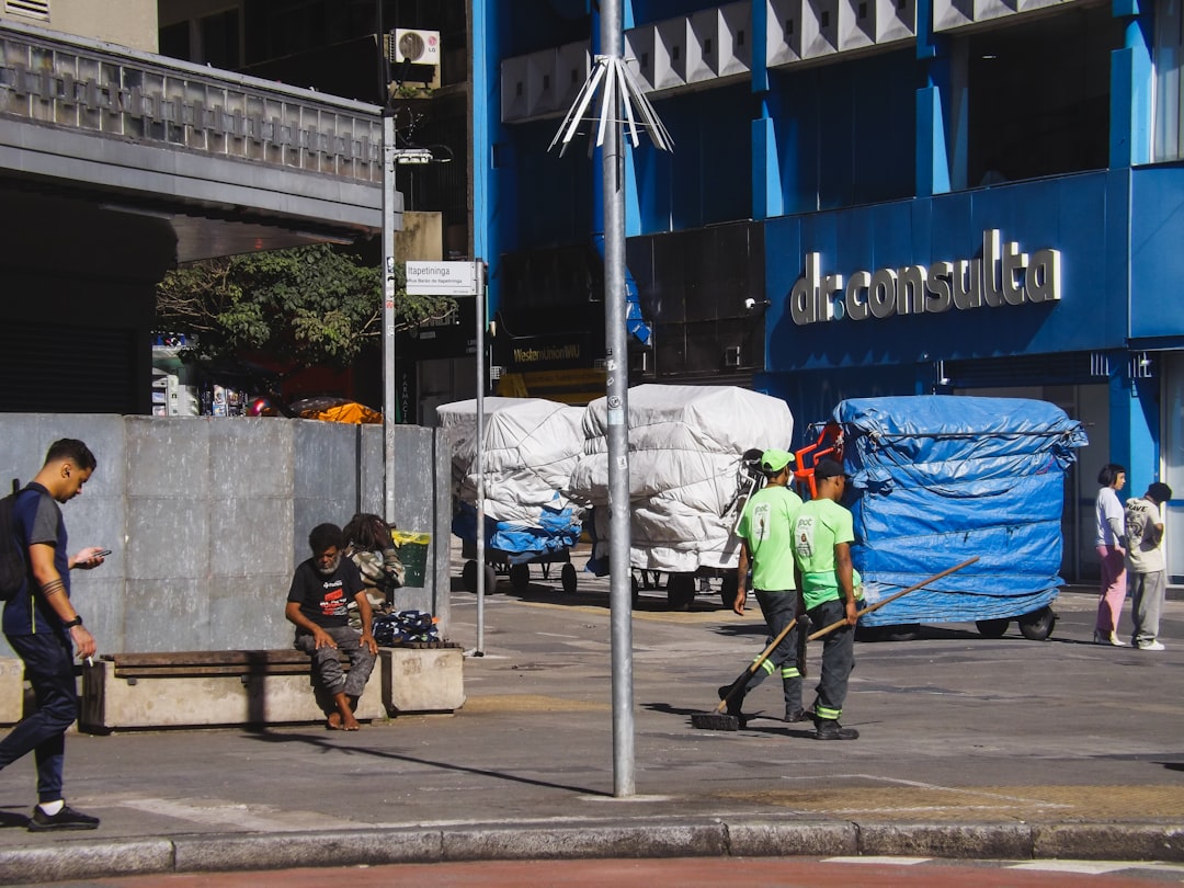 People walk by a building and carts.
