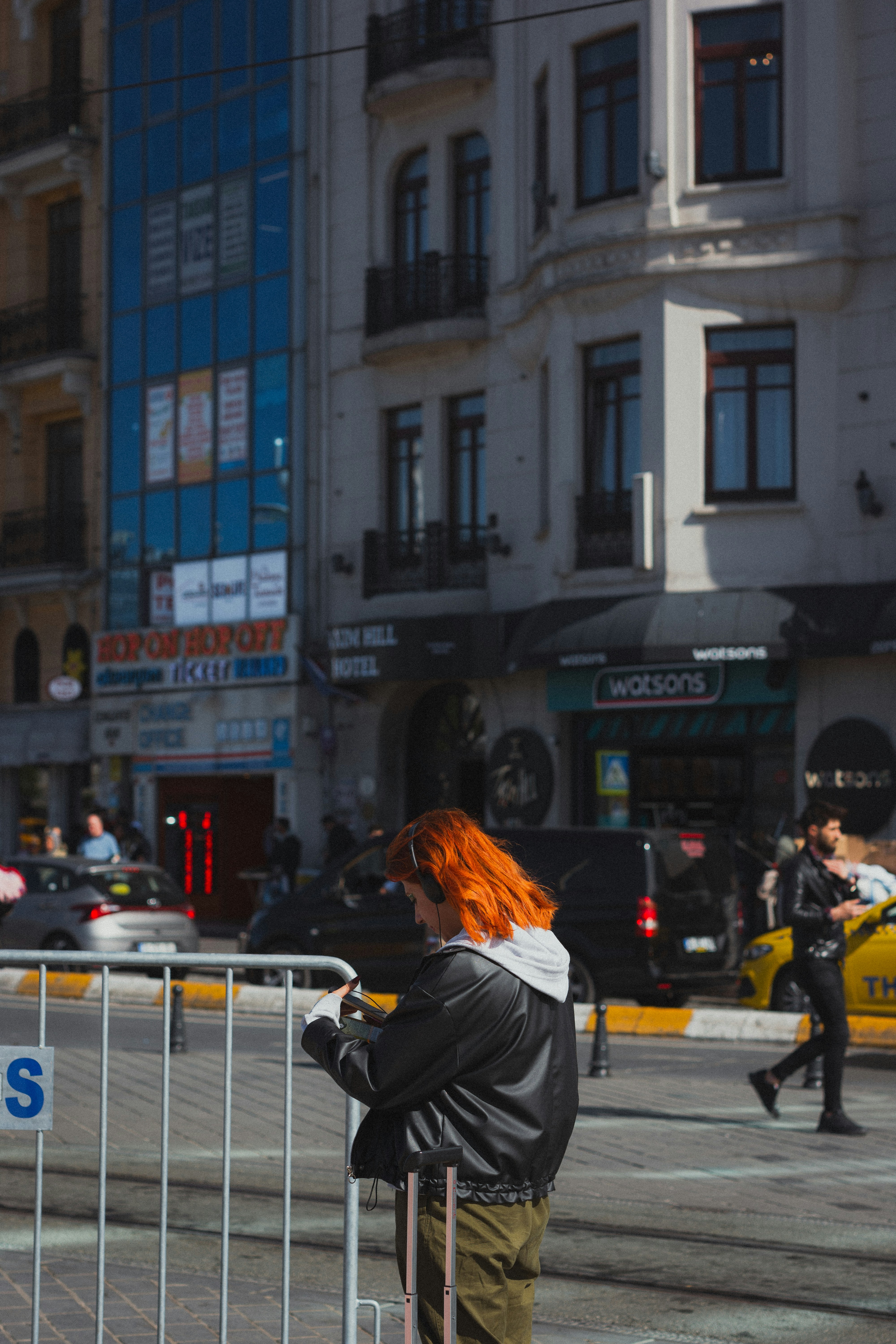 a woman with red hair standing next to a fence