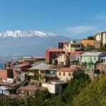 Editorial image of colorful Chilean hillside homes with an Andean backdrop for a culture, history, and adventure travel guide.