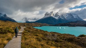 Editorial image of a Patagonia boardwalk trail, turquoise water, and snow-dusted mountains.